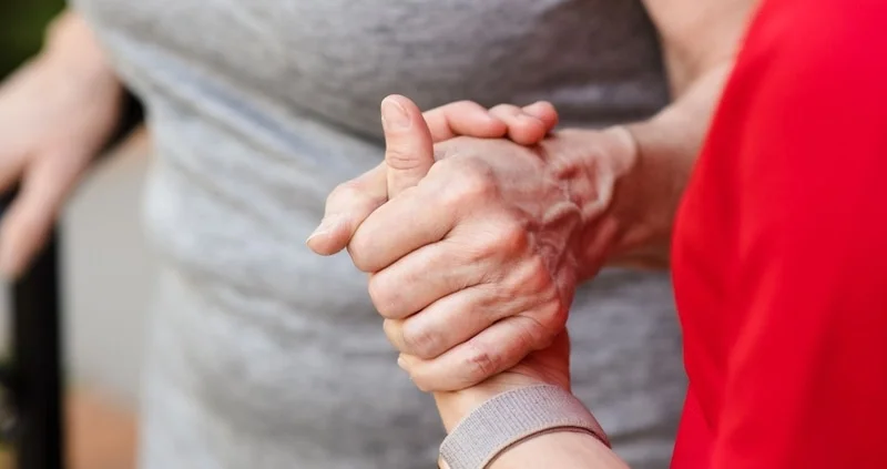 A therapist holding hands with an older adult patient, representing Shift Mobile Therapy and Wellness's in-home care for older adults